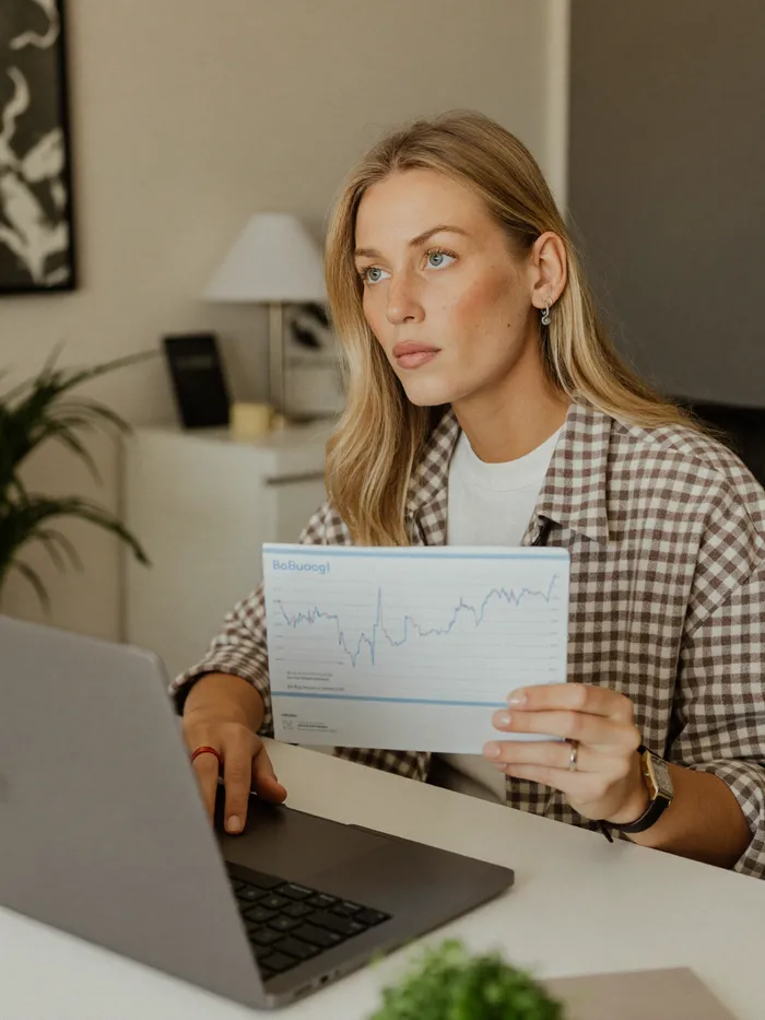 A woman reviewing her budget on a laptop at her home desk, composed